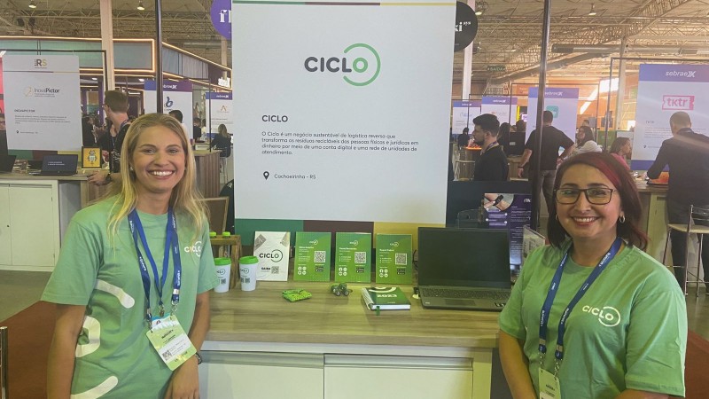 Duas mulheres sorridentes em frente ao estande de uma startup chamada CICLO