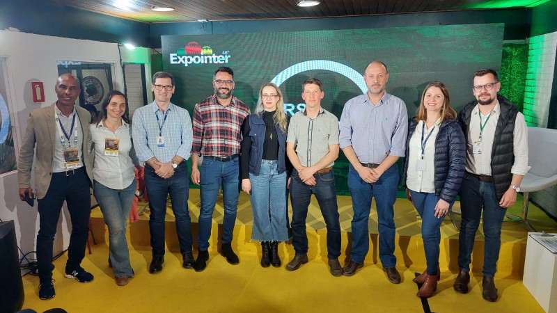 Nove pessoas em frente ao painel do RS Innovation Agro.