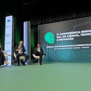 Participantes do painel sentados em frente a tela onde está escrito 5ª Conferência Regional Sul de Ciência, Tecnologia e Inovação